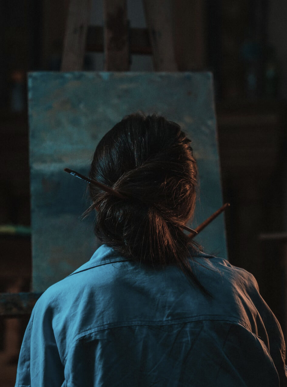 Artist at an easel, seen from behind — creative depth and focused attention