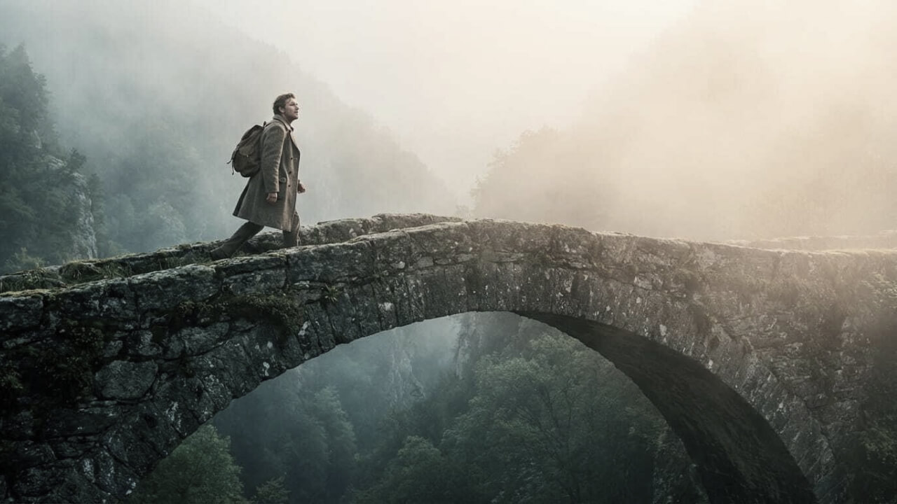 Person crossing an ancient stone bridge through mist — serving what unfolds
